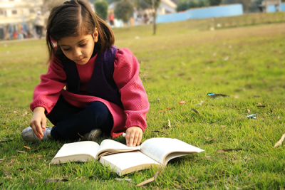 Young girl reading outside on the grass