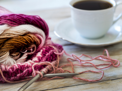 image of pink and white yarn on a table next to a cup of tea