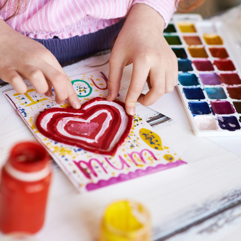 Child making a card with art supplies in the frame
