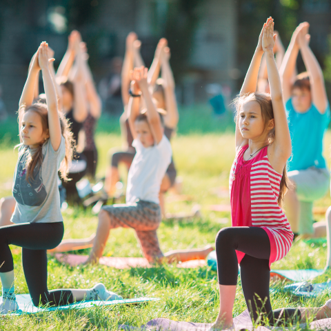 Image of children in a yoga post on mats outside
