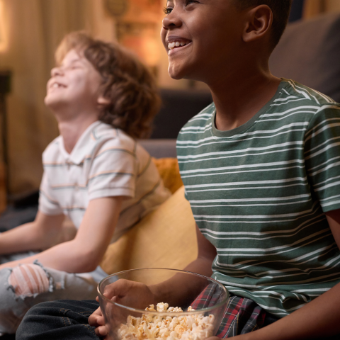 Image of two kids watching a movie and eating popcorn