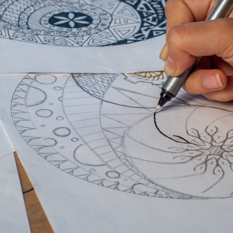 Image of a hand drawing designs on a paper