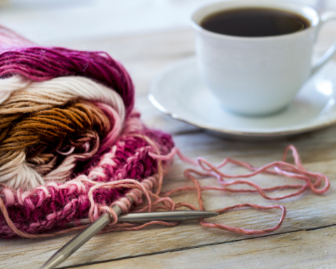 photo of a pink and white knitting project next to a cup of tea