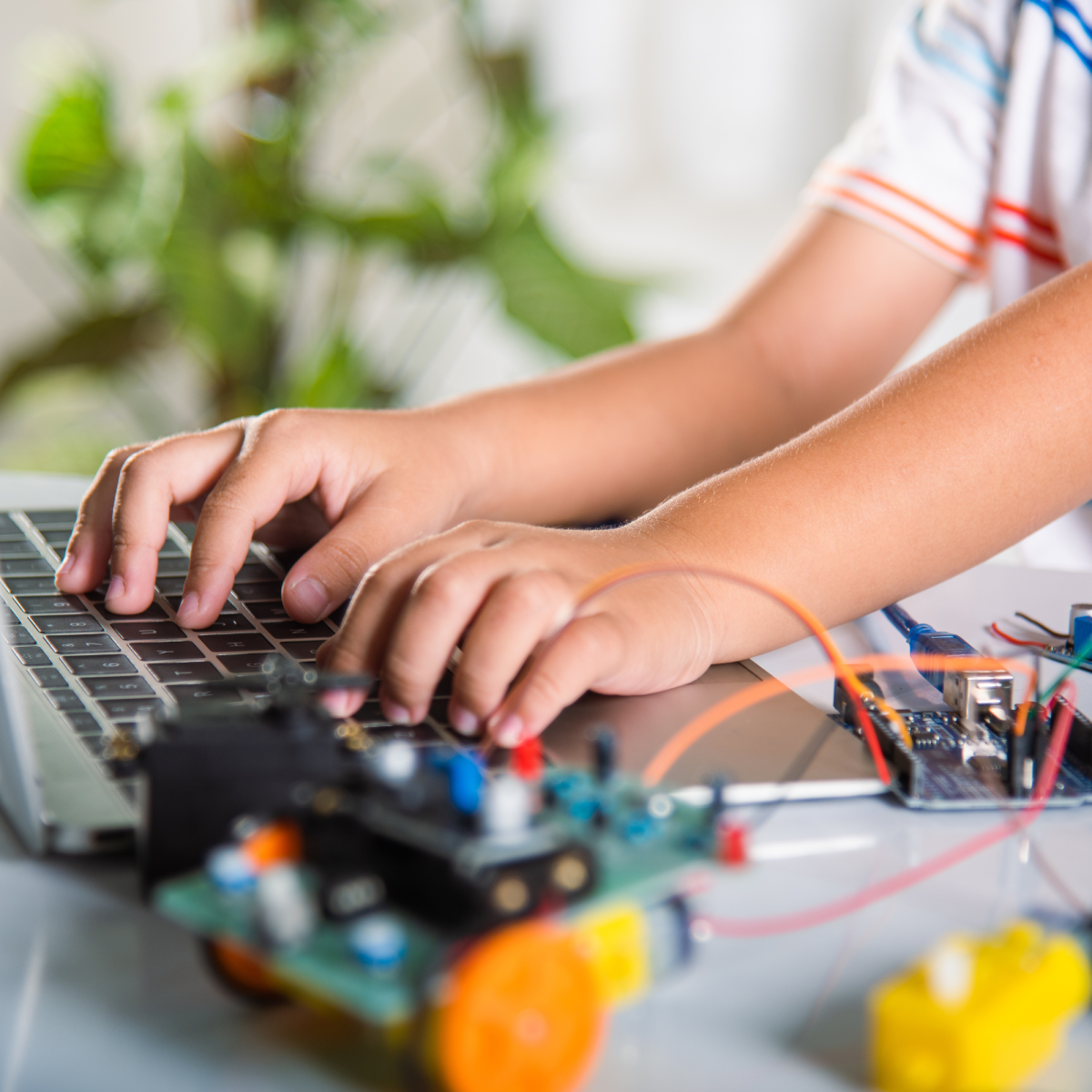 Image of a child at a computer with wires and a hand-built vehicle
