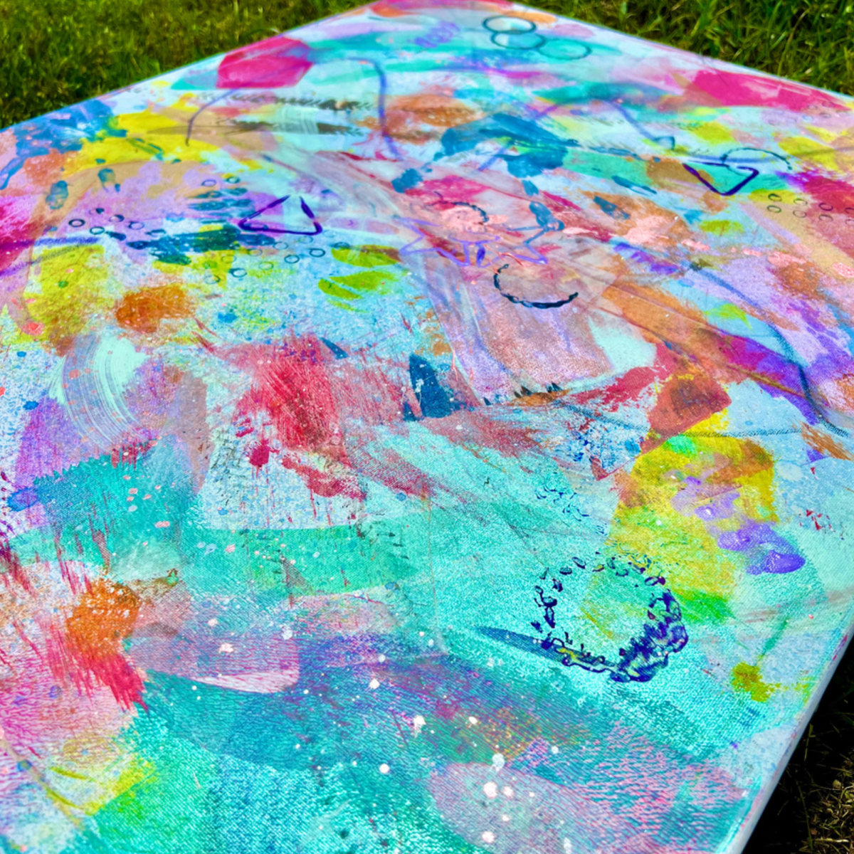 Image of a canvas filled with colorful brushtrokes of paint on grass