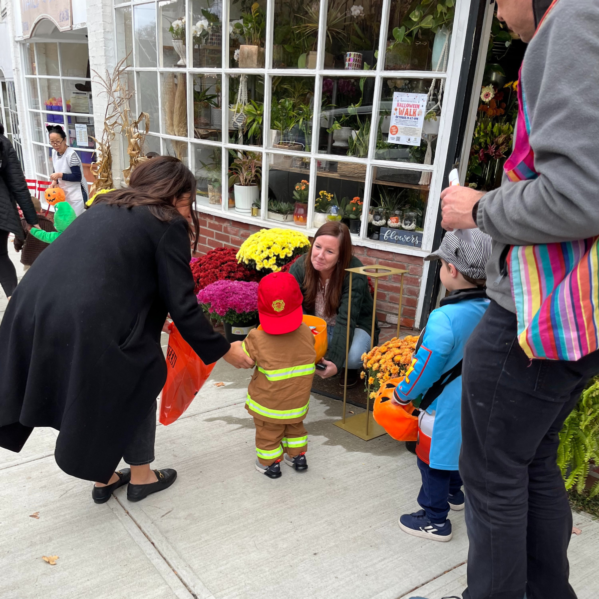 Image of children dressed in costumes in front of a floral shop trick or treating