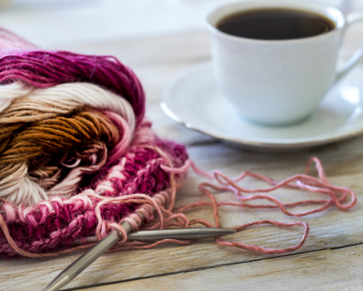 photo of a pink and white knitting project next to a cup of tea