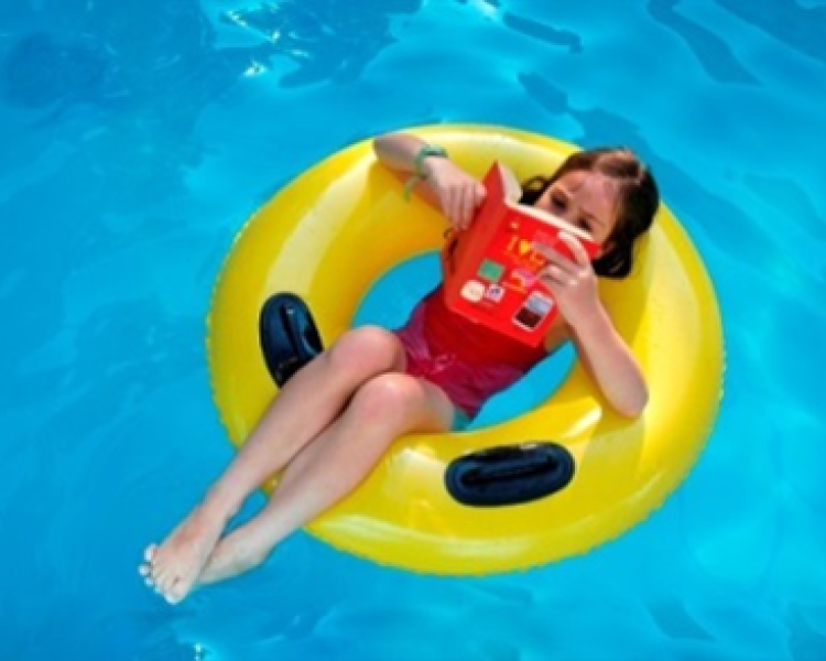Girl reading on pool tube in pool