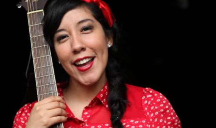 Image of Flor Bromley holding a string instrument in a red dress and red headband